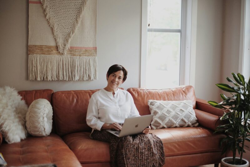 Man in white dress shirt sitting on red couch using MacBook