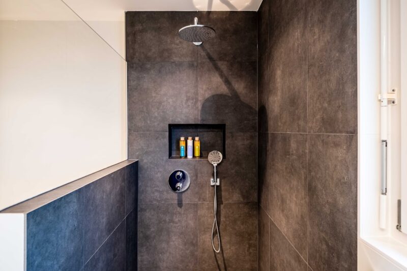 Stainless steel shower head on white ceramic wall tiles