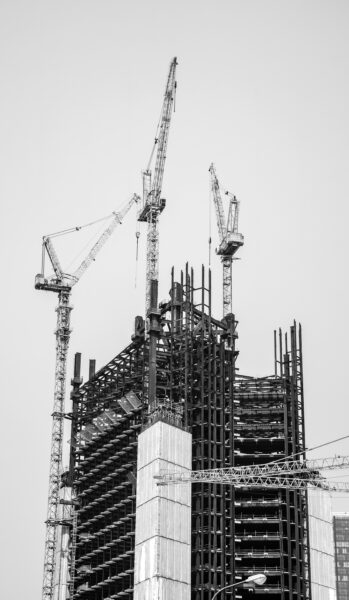 Grayscale photo of crane near building