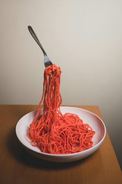 Red pasta on white ceramic plate