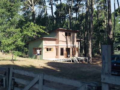 Brown wooden house near green trees during daytime