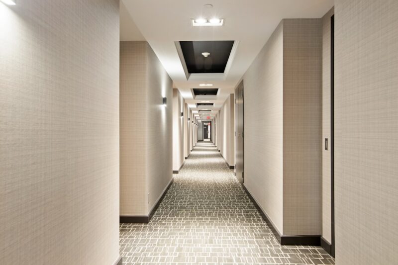 White and black hallway with lights turned on in the middle.