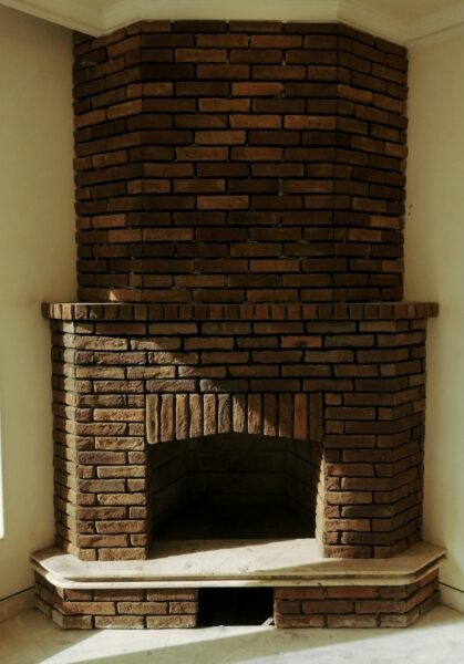 A brick fireplace in a corner of a room.
