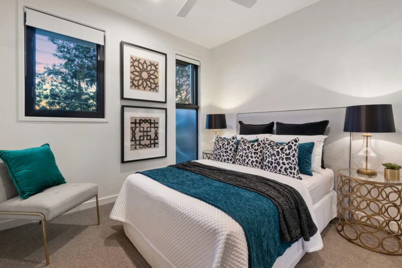 A bedroom with a bed, chair, and pictures on the wall.