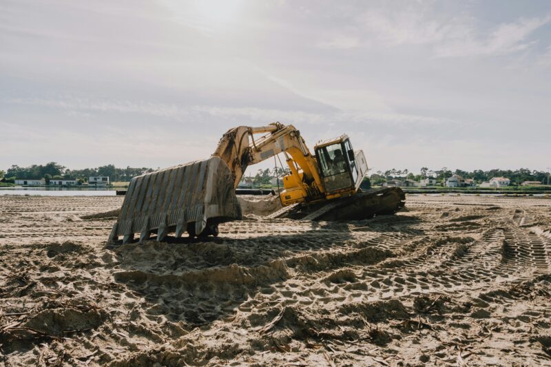 A bulldozer digging in the sand on a beach