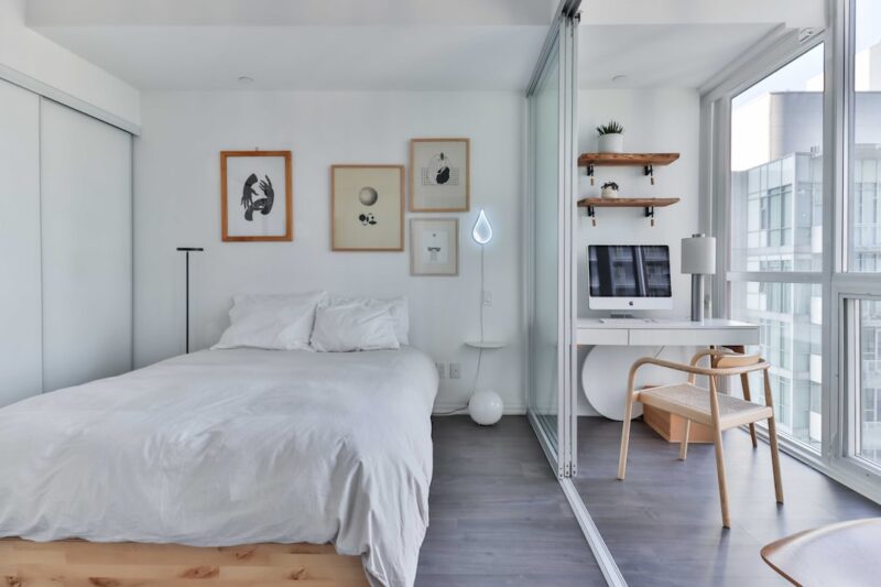 A bedroom with a bed, desk, and a window