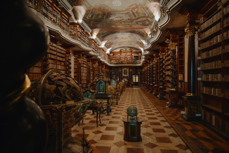 A long room with many bookshelves and a clock.