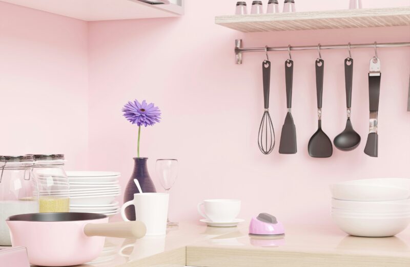 A pink kitchen with utensils hanging on the wall