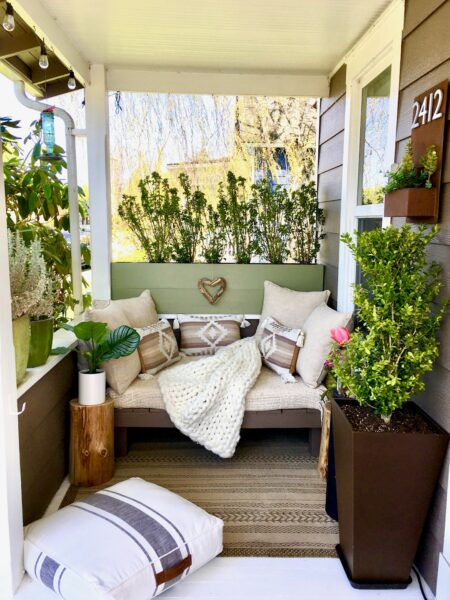 A couch with pillows on a covered porch.