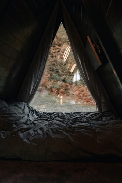 A bed in a cozy small room with a window.