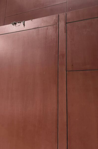 A red building with a clock on the side of it.