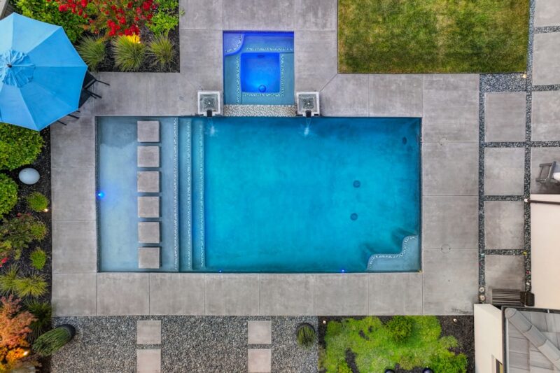 An aerial view of a swimming pool surrounded by greenery.