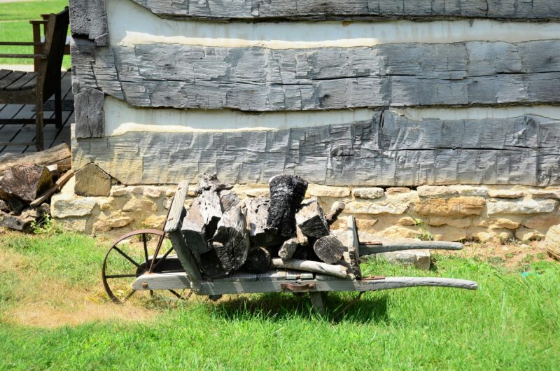 A wagon with logs on it in front of a building