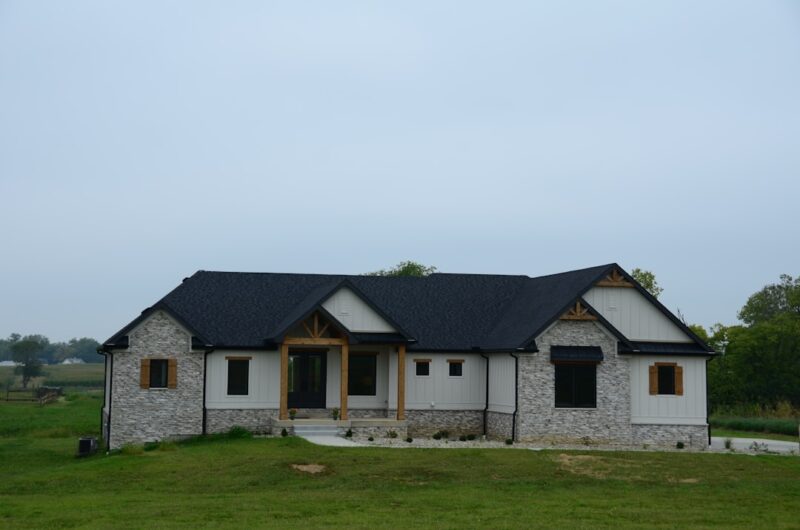 Stone house with black roof and windows.