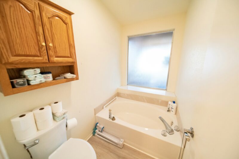 A white toilet sitting next to a bath tub in a bathroom.