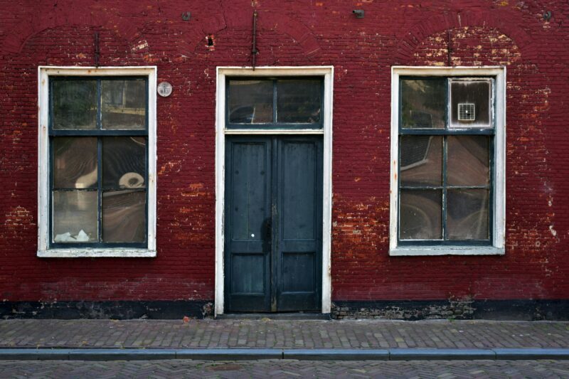 A red brick building with two windows and a blue door