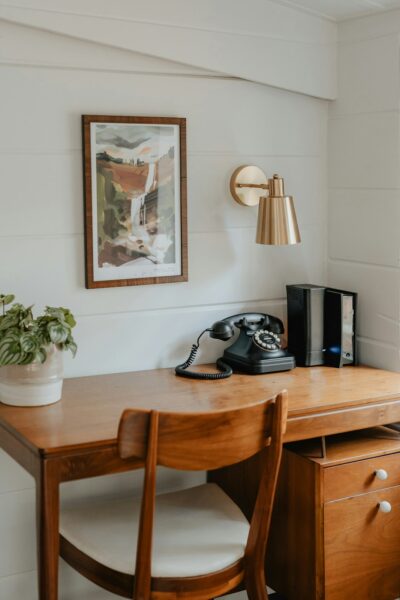 A wooden desk with a phone on top of it.
