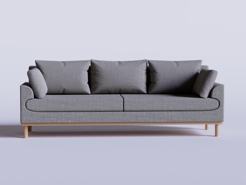 A gray couch with four pillows on it