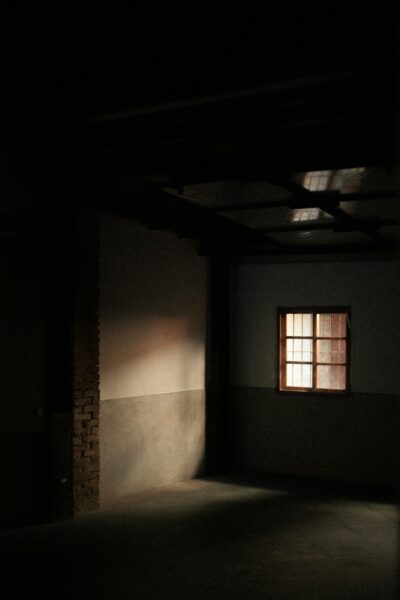 A dark room with a window and a brick wall.