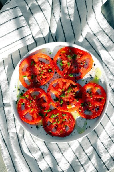 A white plate topped with sliced tomatoes on top of a table.