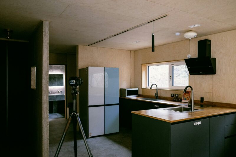 A kitchen with a sink, a refrigerator, and a tripod