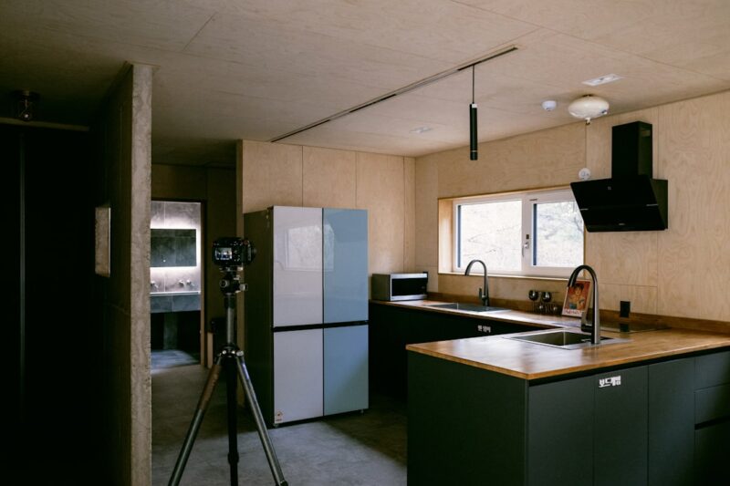 A kitchen with a sink, a refrigerator, and a tripod.