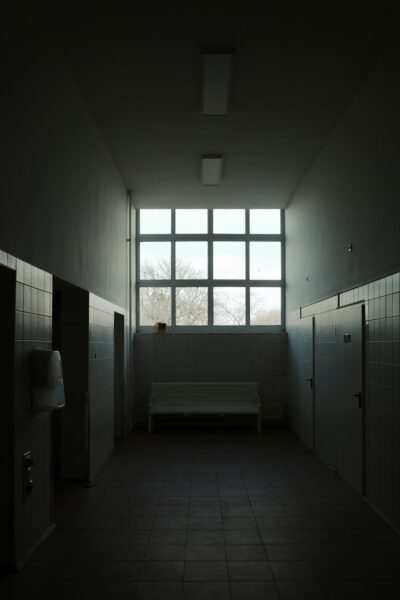 A dimly lit room with a bench and urinals.