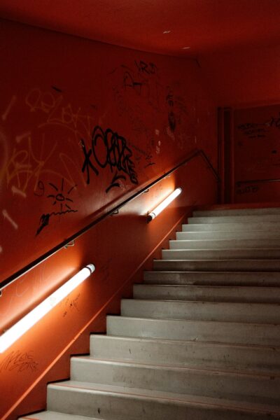 A staircase with graffiti on the wall and a light on.