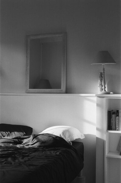 A black and white photo of a bed in a bedroom.