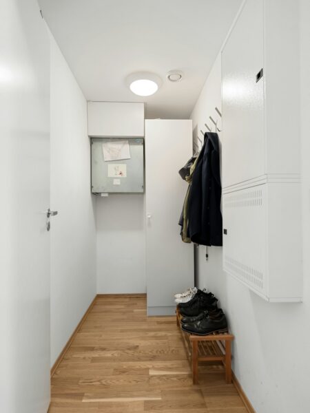 A white hallway with a coat rack and shoes