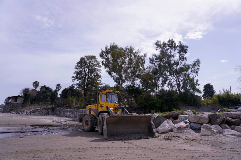 A yellow bulldozer is on a beach