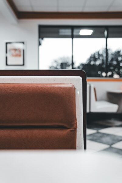 A stylish modern restaurant interior featuring a leather booth with natural light through large windows.