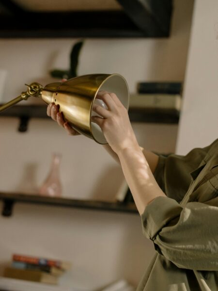 Person changing a lightbulb in a stylish home setting with bookshelves in the background.
