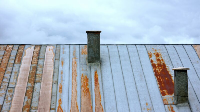 A rusted metal roof with two chimneys