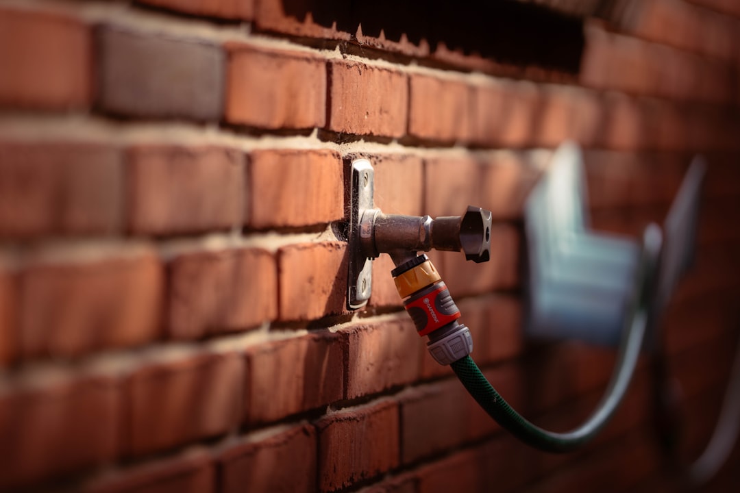 A faucet and garden hose attached to brick wall.