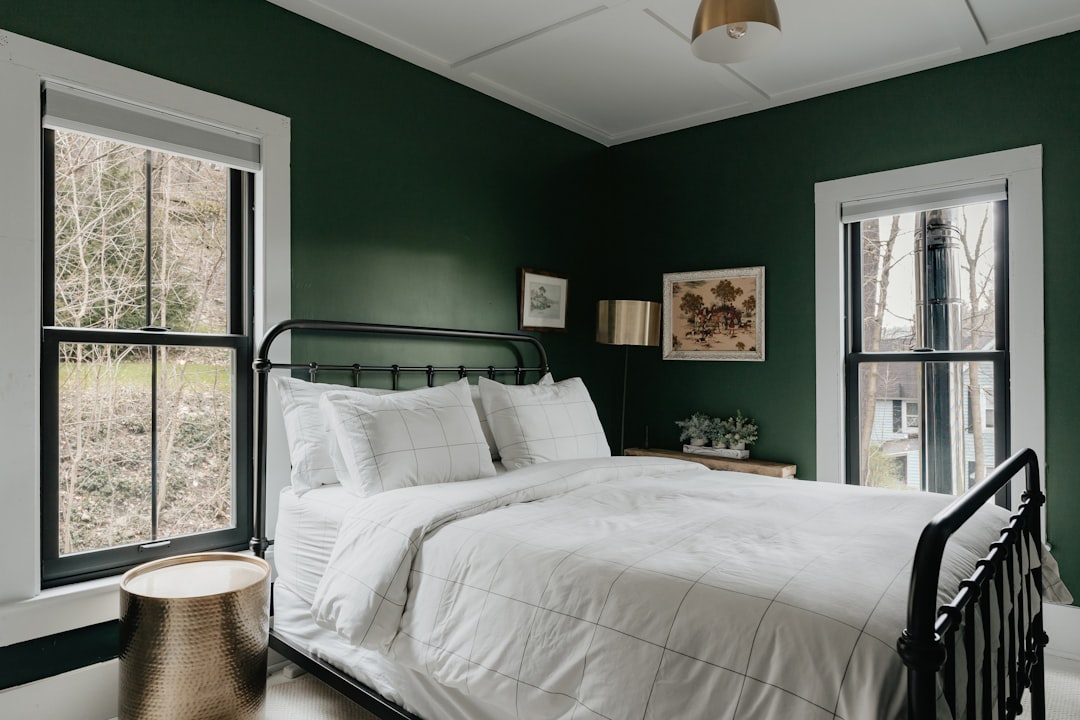 Green bedroom walls balanced with light bedding and warm accents