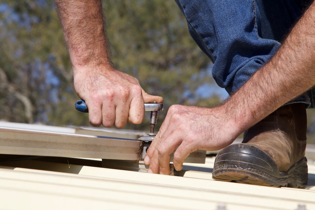 Hands using a tool to fasten metal roofing.