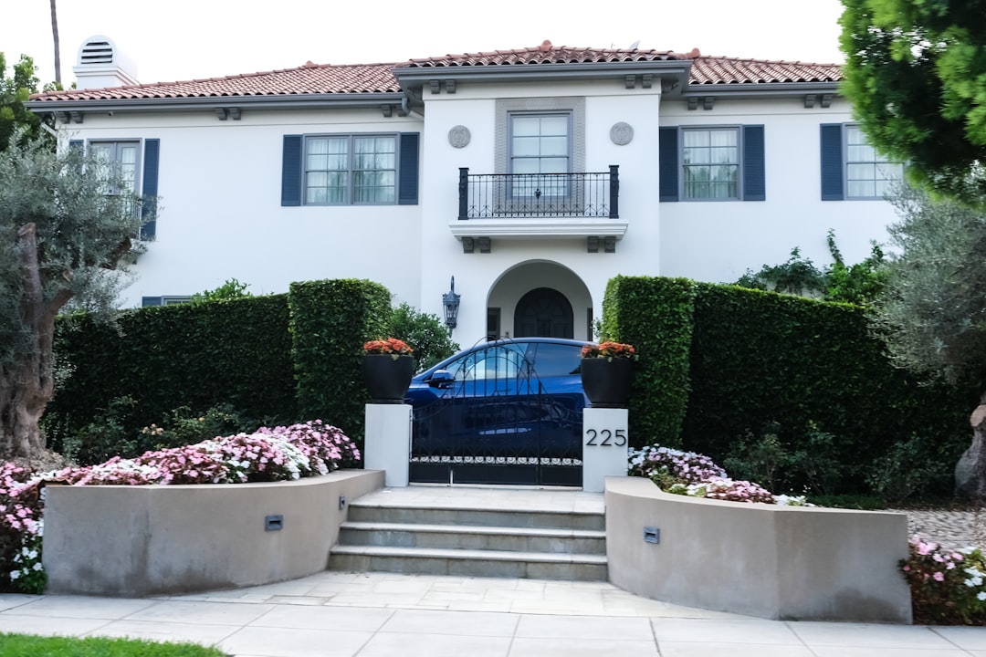 A blue car parked in front of a white house.