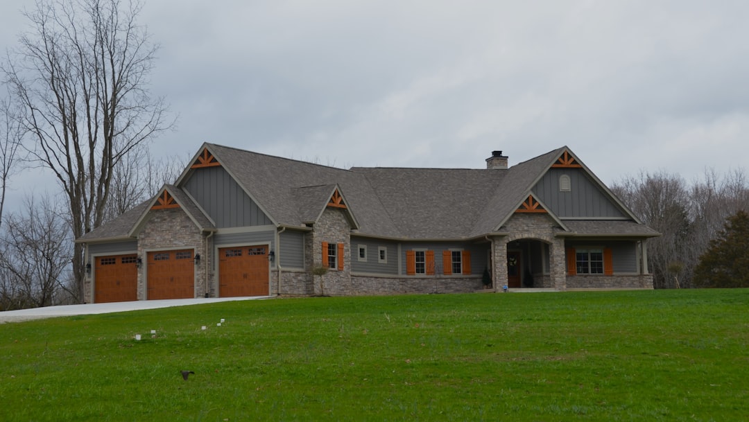 a large house with two garages on a grassy hill