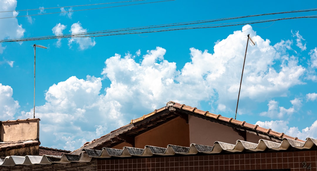 Rooftops and antennas against a bright blue sky.