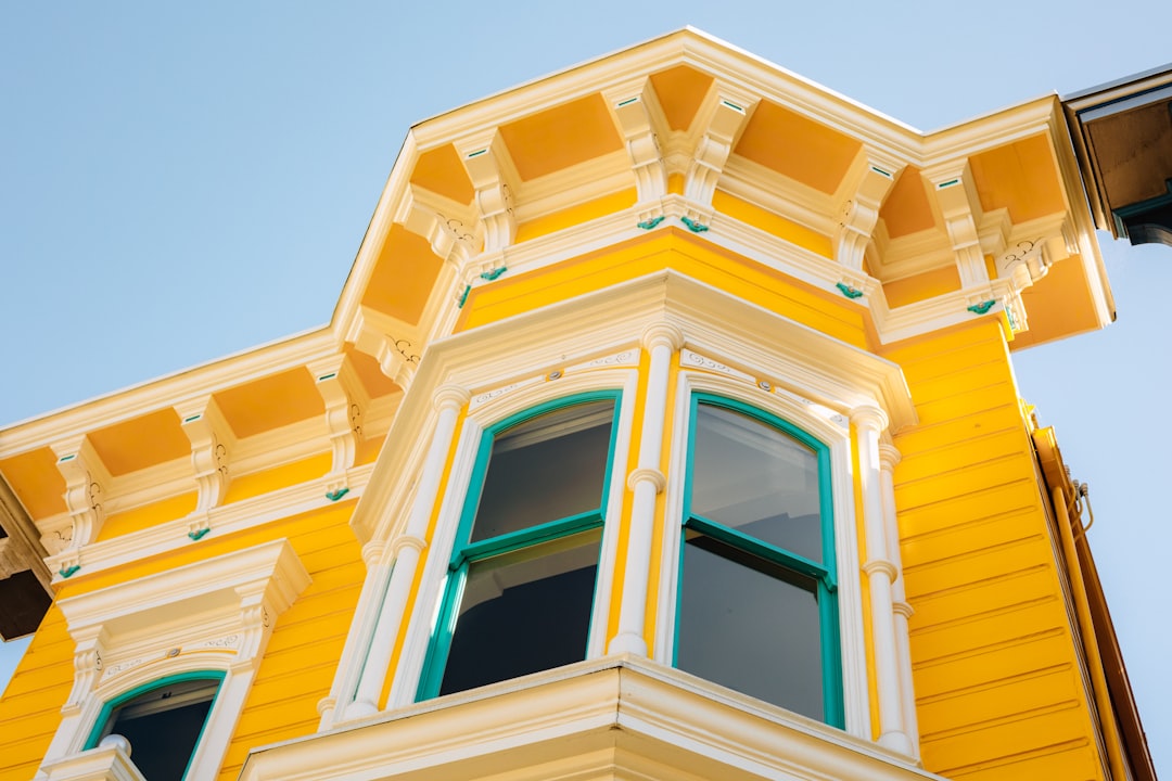 Bright yellow victorian house with ornate trim.