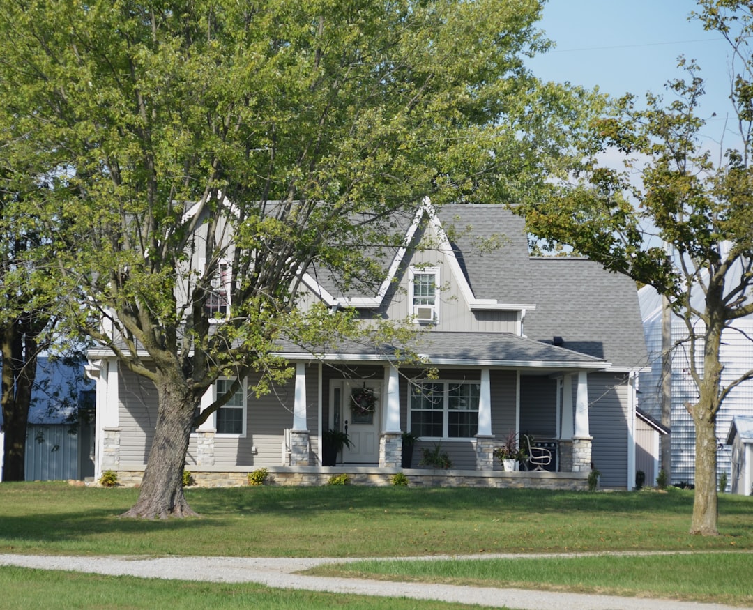 A grey house with a porch and trees.