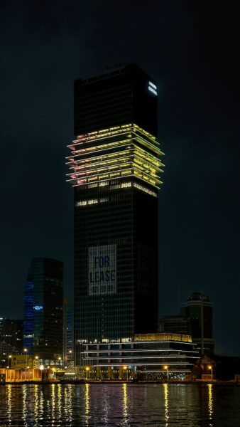 A night view of a towering skyscraper with colorful lights reflecting in the water in Ho Chi Minh City.