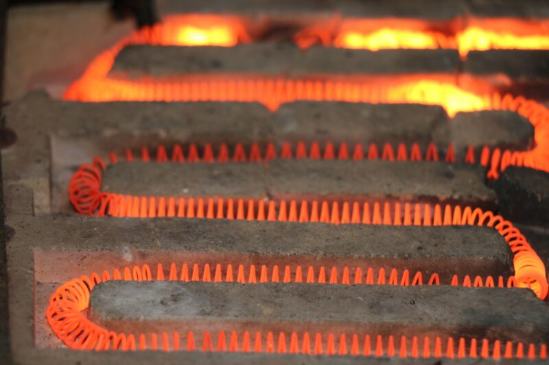 Detailed view of a glowing electric heating element with a coiled structure emitting heat.