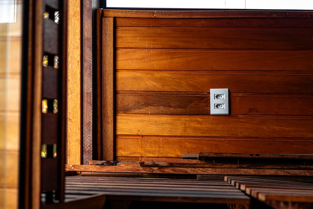 A white electrical outlet on a warm wooden wall.