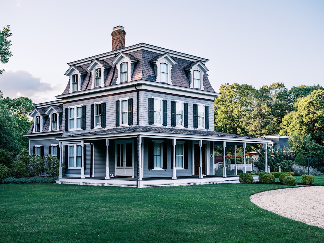 A large gray victorian house with a wraparound porch.