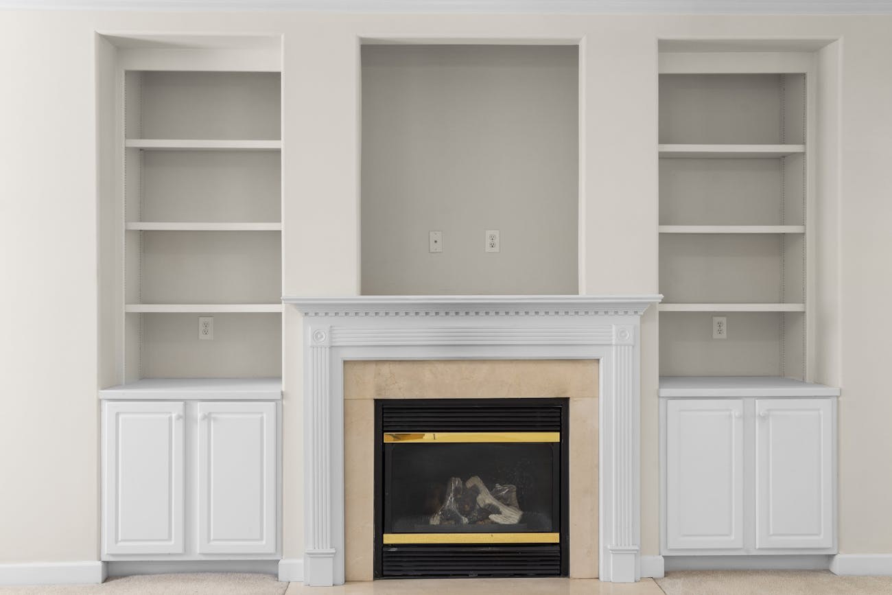 White built-in bookcases around a fireplace in a bright living room