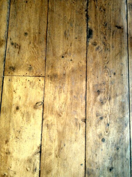 A weathered old wood floor with visible grain and knots, showing signs of wear.