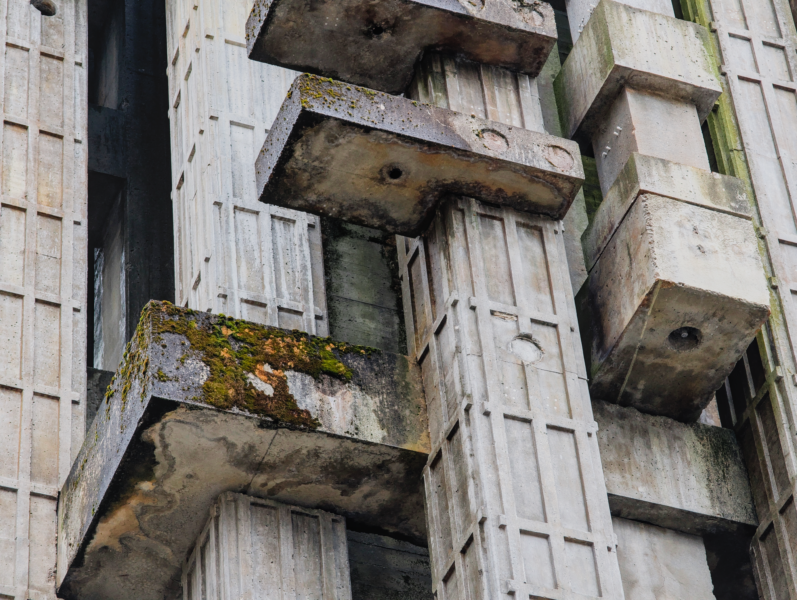 A close-up of a moss-covered brutalist concrete structure showcasing geometric design.