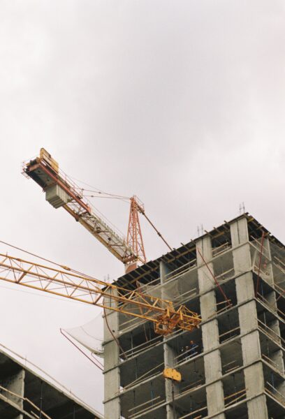 A high-rise building under construction with visible tower cranes and concrete structure.